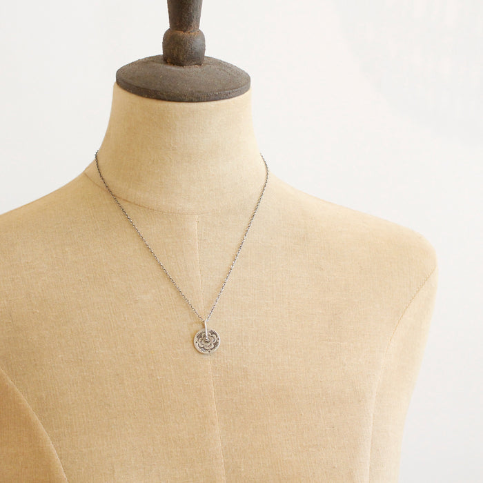 A mannequin wearing the pinned columbine disc necklace