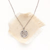 The pinned columbine disc necklace styled on tan linen