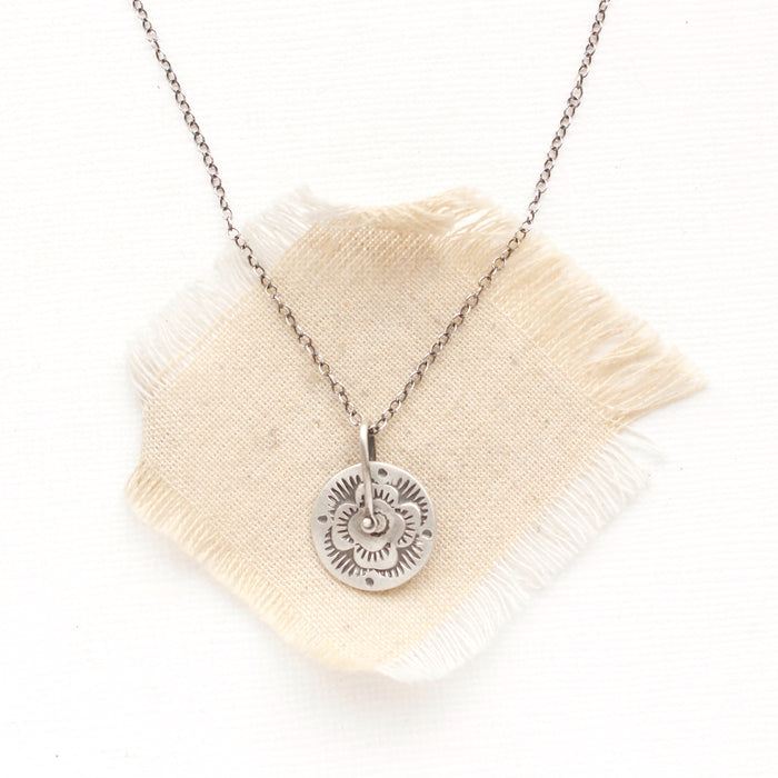 The pinned columbine disc necklace styled on tan linen
