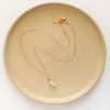 The pinned gold herkimer diamond necklace styled on a tan plate to show the adjustable lobster clasp closure