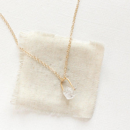 The pinned gold herkimer diamond necklace styled on tan linen
