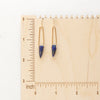 The lapis spear earrings on a wooden ruler to show size reference