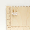 The pinned organic pearl earrings on a wooden ruler for size reference