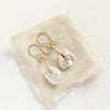 The pinned organic pearl earrings styled on tan linen