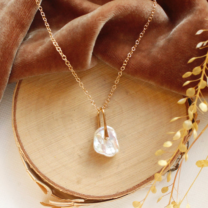 The pinned organic pearl necklace styled on wood with orange velvet and dried grass