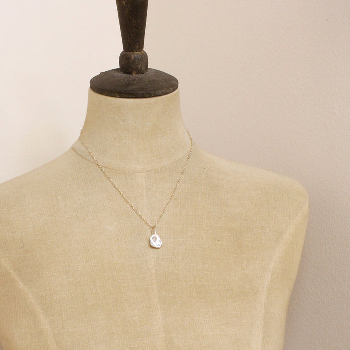A mannequin wearing the pinned organic pearl necklace
