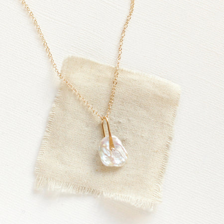 The pinned organic pearl necklace styled on tan linen