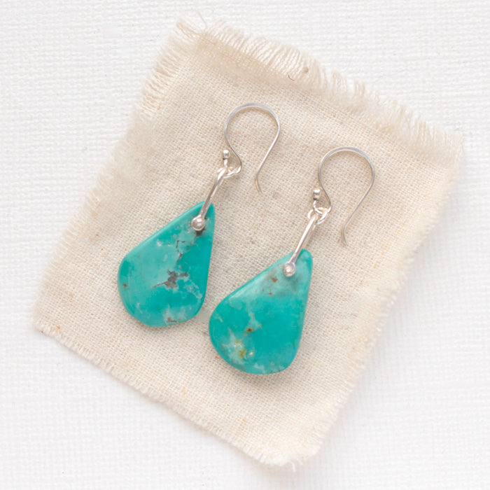 The pinned turquoise earrings styled on tan linen