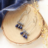 The pinned vinca arch earrings styled on wood with blue velvet and dried grass