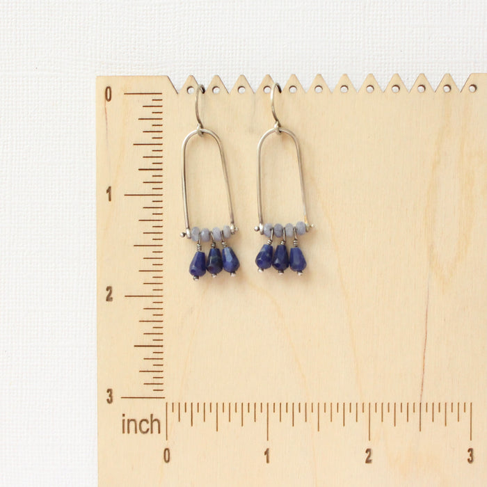 The pinned vinca arch earrings on a wooden ruler for size reference