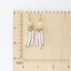 The prehnite and pearl earrings on a wooden ruler for size reference