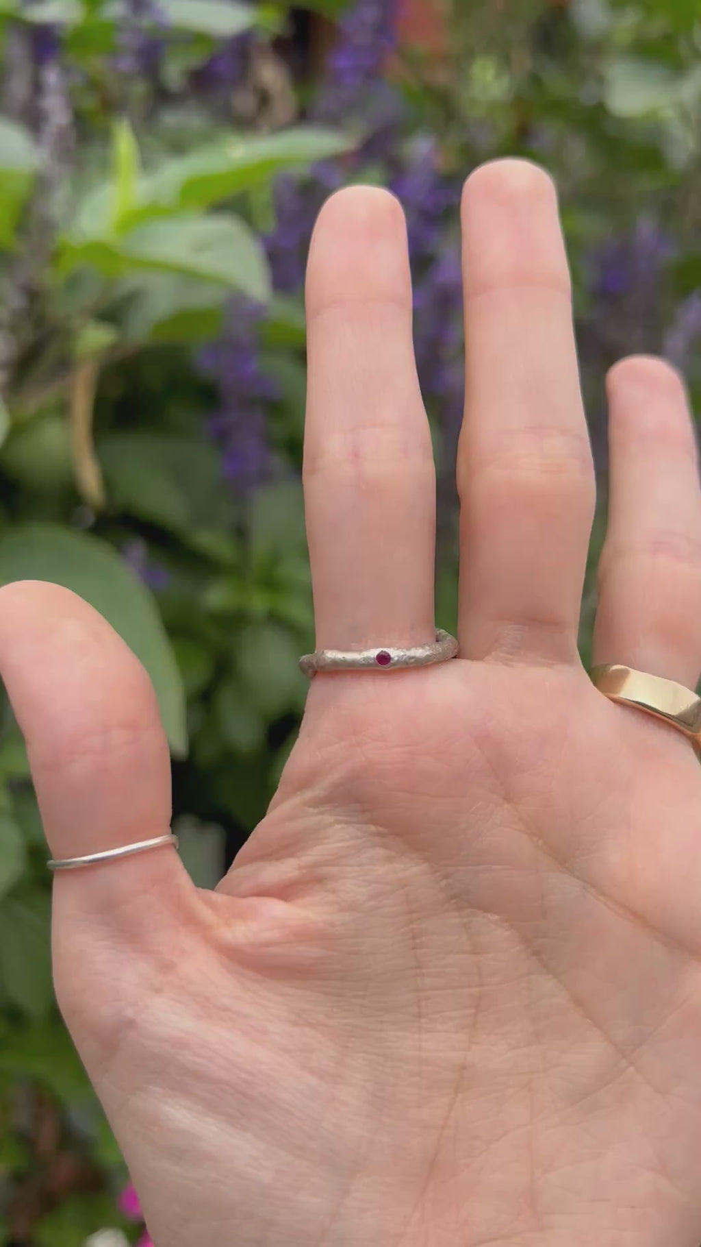 The thulite ring being worn on a hand