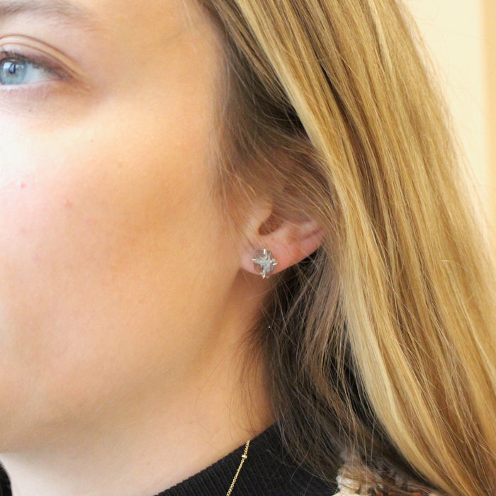 The prong set aquamarine earrings being worn in an ear to show size reference