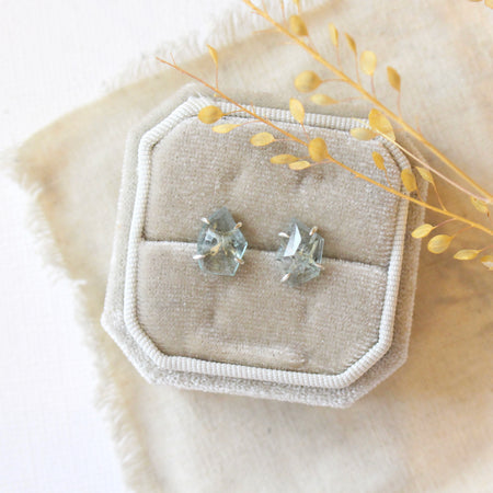 The prong set aquamarine post earrings styled on a velvet box with tan linen and dried grass