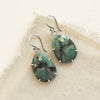 The prong set emerald earrings styled on tan linen