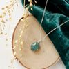 The prong set emerald necklace styled on wood with green velvet and dried grass