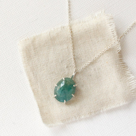 The prong set emerald necklace styled on tan linen