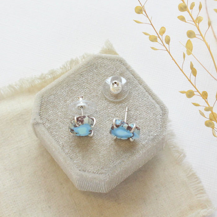 The lavender turquoise post earrings styled on a velvet box to show the comfort clutch ear backs. 