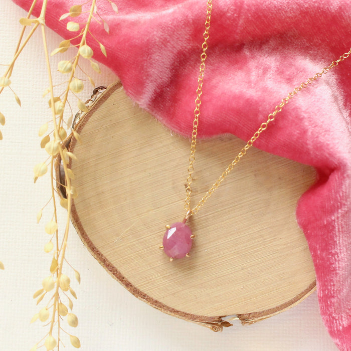 The prong set ruby necklace styled on wood with hot pink velvet and dried grass