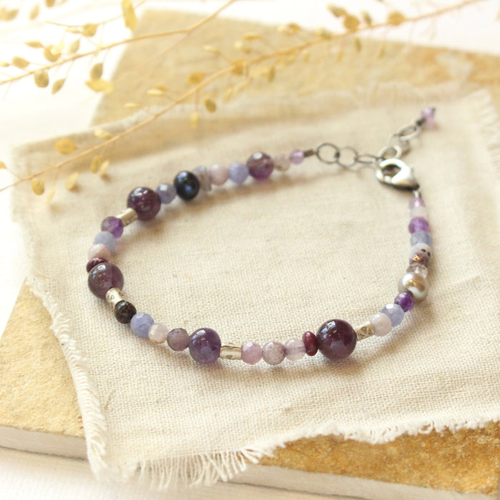 The purple gemstone bracelet styled on a tan rock