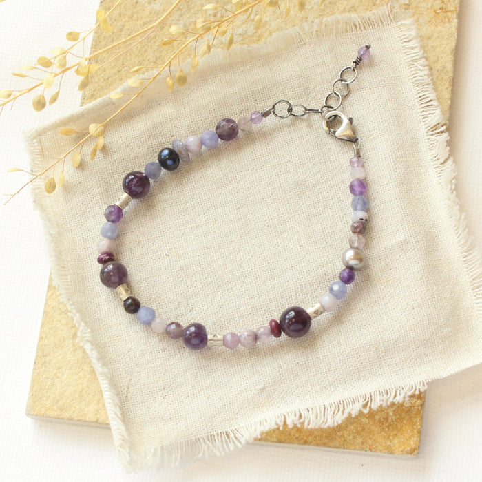 The purple haze gemstone bracelet styled on a tan rock with linen and dried grass
