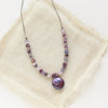 The purple rain necklace styled on tan linen