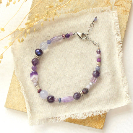 The purple rain gemstone bracelet styled on a tan rock with linen and dried grass