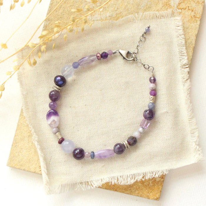 The purple rain gemstone bracelet styled on a tan rock with linen and dried grass