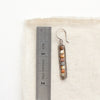 A rainbow agate beaded bar earring next to a ruler for size reference