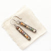 The rainbow agate beaded bar earrings styled on tan linen