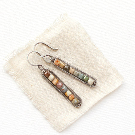 The rainbow agate beaded bar earrings styled on tan linen