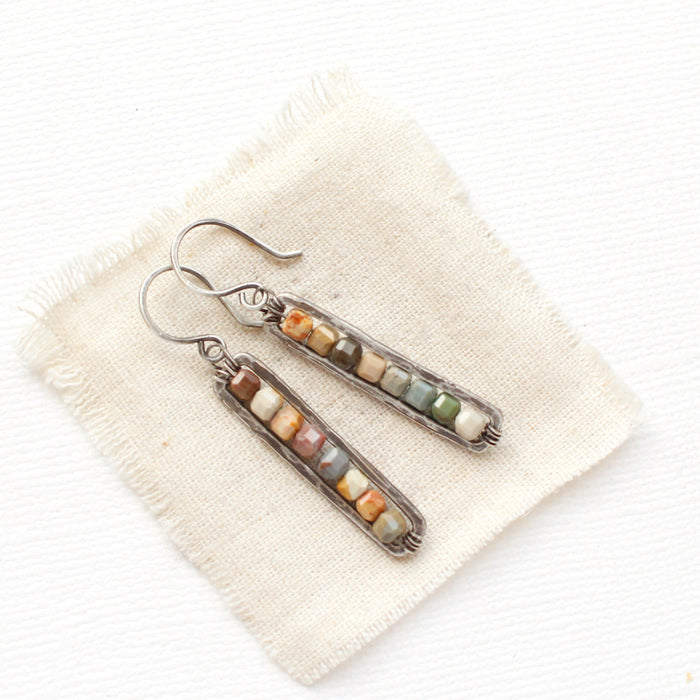 The rainbow agate beaded bar earrings styled on tan linen