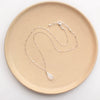 The rainbow moonstone silver bar necklace styled on a tan plate to show the adjustable lobster clasp closure