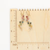 The rainbow vine earrings on a wooden ruler for size reference