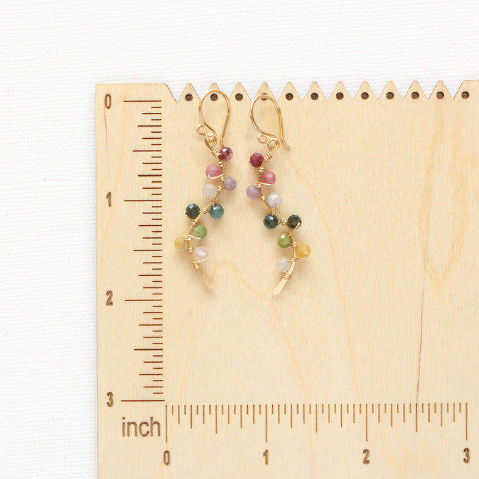 The rainbow vine earrings on a wooden ruler for size reference