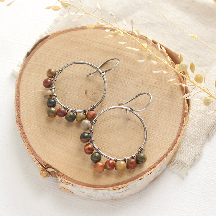 The jasper hoop earrings styled on wood with dried grass and tan linen