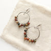 The jasper hoop earrings styled on tan linen