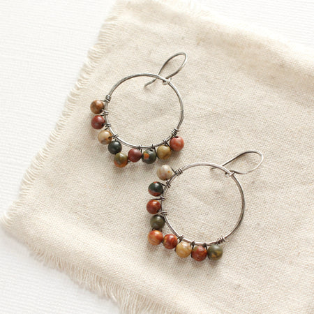 The jasper hoop earrings styled on tan linen