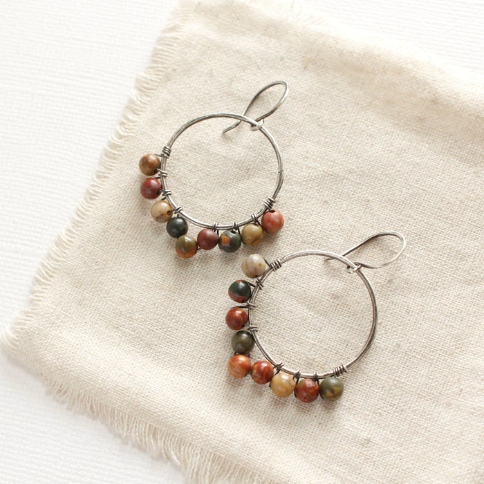 The jasper hoop earrings styled on tan linen