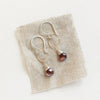 The rhodolite garnet silver hoop earrings styled on tan linen