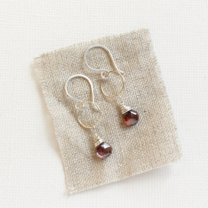 The rhodolite garnet silver hoop earrings styled on tan linen