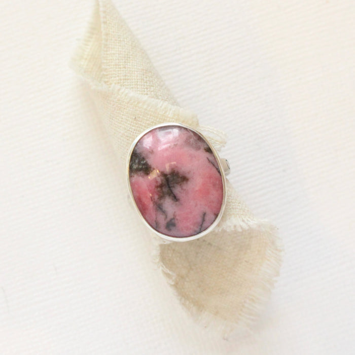 The rhodonite ring styled on rolled tan linen