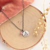 The sprout and rhodonite charm necklace styled on wood with pink velvet and dried grass