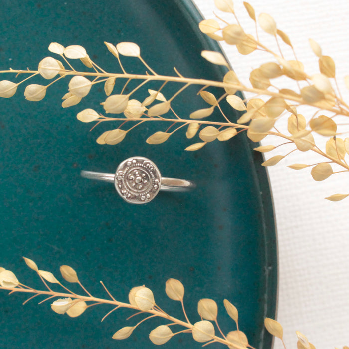 The silver roma embossed stacking ring styled on a blue plate with dried grass