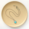 The royston turquoise stamped arch necklace styled on a tan plate to show the adjustable lobster clasp closure