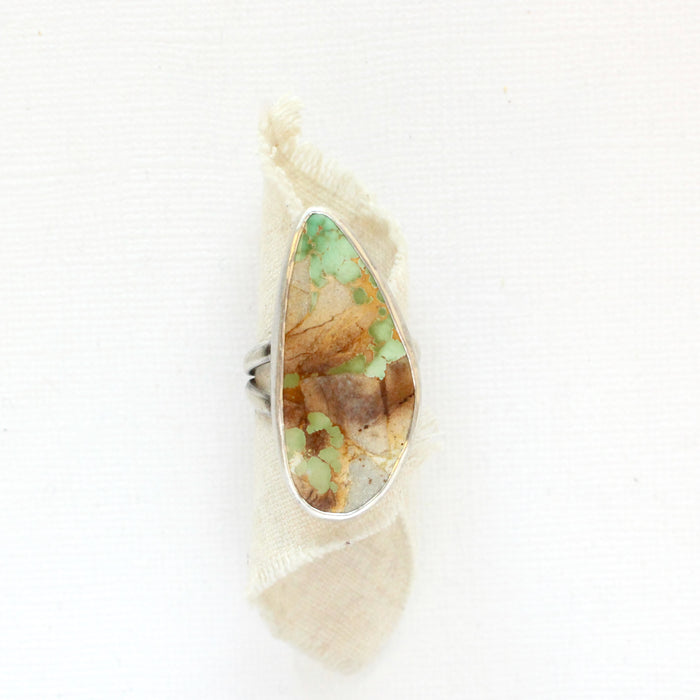 The stunning green and brown royston turquoise statement ring styled on rolled tan linen