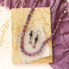The ruby and leather earrings styled on on a tan rock with the matching necklace