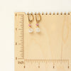 The ruby and moonstone drop earrings on a wooden ruler for size reference