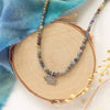 The sapphire and elephant necklace styled on wood with blue velvet and dried grass