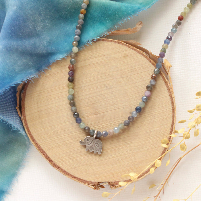The sapphire and elephant necklace styled on wood with blue velvet and dried grass